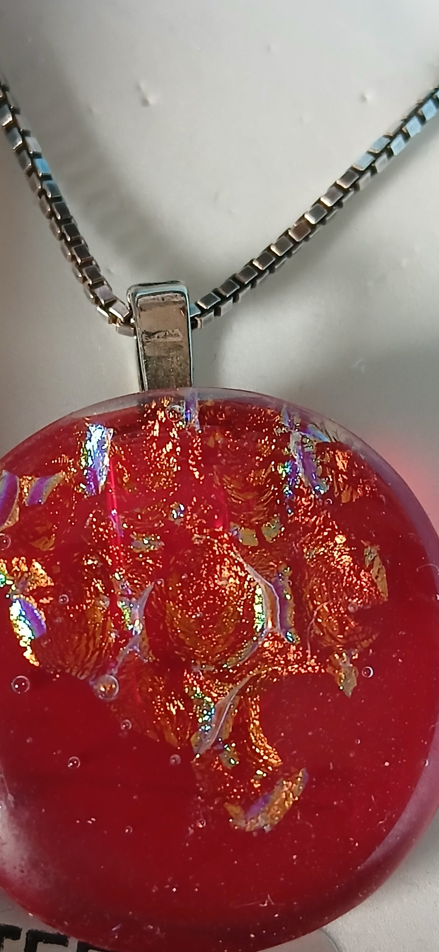 Main Description: "Ignite your style with this mesmerizing Fire Ice dichroic glass pendant that captures the essence of flickering flames frozen in time. This stunning handcrafted piece features a captivating blend of fiery red, molten gold, emerald green, and rich copper tones that shift and dance with every movement. The dichroic glass creates an enchanting play of light, making each viewing angle reveal new depths of colour and brilliance.