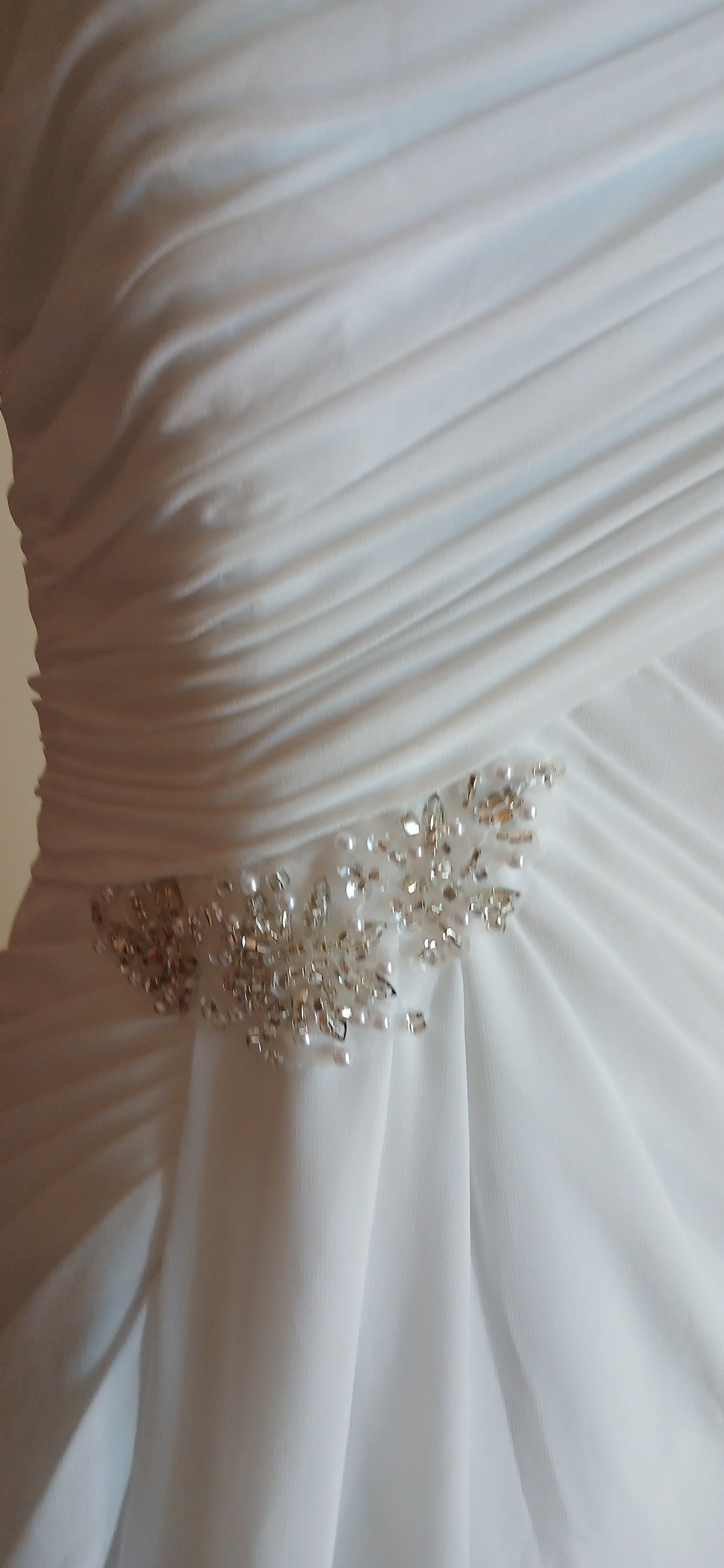 Close-up of a white pleated fabric with a decorative silver design